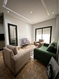 sala de estar con 2 sofás y TV en joli appartement a jardin de Carthage en Túnez