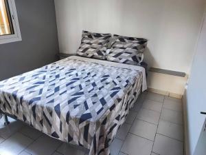 a small bedroom with a bed with a checkered comforter at La Caz Serins ETANG SALE in Le Lambert