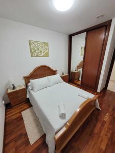 a bedroom with a large bed and a mirror at Grupo Gontad Apartamento Asalo Malpica in Malpica