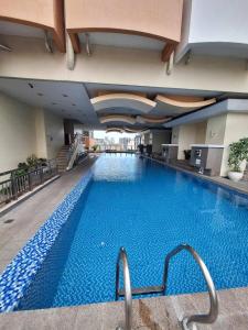 a large swimming pool in a hotel building at BirchTower Studio Condo with Balcony & Pool - Carosa Staycation in Manila