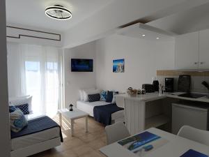 a white living room with a couch and a kitchen at Nautilus City Studios & Apartments in Rhodes Town