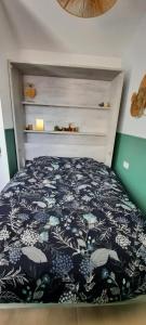 Schlafzimmer mit einem Bett mit einer schwarzen und weißen Bettdecke in der Unterkunft Agréable studio lumineux pour escapade à deux ! 1 pièce avec salle de bain - 14m2 - Exterieur privatif - in Saint-Laurent-de-la-Salanque