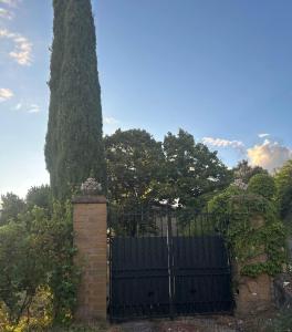 um portão preto com uma grande árvore atrás dele em Flat - Casale Angela em Bolsena