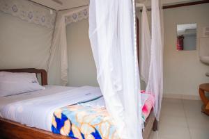 a bedroom with a canopy bed with white curtains at KaribuGuestHouse in Fort Portal