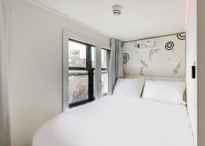 Cama blanca en habitación con ventana en SUPPER Hotel en Ámsterdam