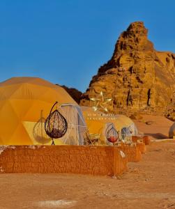 a group of domes in the desert with a rock at RUM SUNRlSE LUXURY CAMP in Wadi Rum