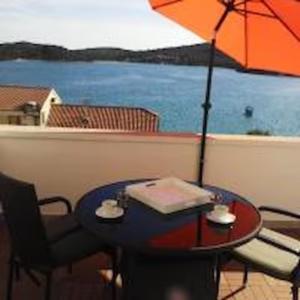 a table with an umbrella and chairs with a view of the water at Apartments Perina in Tisno