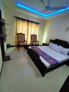 a bedroom with a large bed and two chairs at Peridot Vacation Inn, Bahria in Islamabad