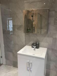 ein Badezimmer mit einem weißen Waschbecken und einem Spiegel in der Unterkunft 230 Councillor Lane in Cheadle