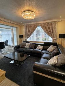 a living room with a leather couch and a glass table at 230 Councillor Lane in Cheadle