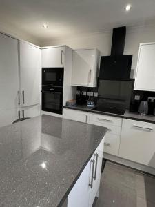 una cucina con armadi bianchi e piano di lavoro nero di 230 Councillor Lane a Cheadle