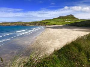 a sandy beach with the ocean and mountains in the background at Swn y Môr - 1 Bedroom Cottage - Whitesands in St. Davids