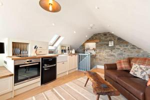 a living room with a couch and a kitchen at Swn y Môr - 1 Bedroom Cottage - Whitesands in St. Davids