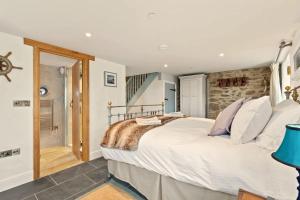 a bedroom with a large bed and a stone wall at Swn y Môr - 1 Bedroom Cottage - Whitesands in St. Davids