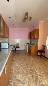 a large kitchen with pink walls and wooden cabinets at ЖК «Нурсая» in Astana