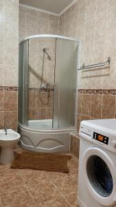 een badkamer met een douche en een wasmachine bij ЖК «Нурсая» in Astana