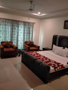 a bedroom with a large bed and two chairs at Peridot Vacation Inn, Bahria in Islamabad