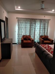 uma sala de estar com duas cadeiras e um sofá em Peridot Vacation Inn, Bahria em Mingora