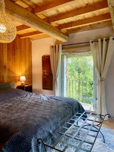 a bedroom with a bed and a large window at Le 1830 in Églisolles