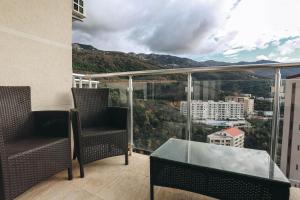 d'un balcon avec deux chaises et une table en verre. dans l'établissement Status-M Apartments Sunny Side, à Becici