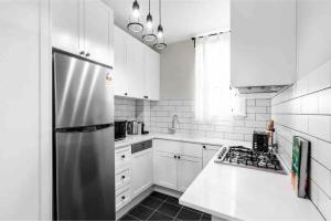 a kitchen with white cabinets and a stainless steel refrigerator at Green Stays in Sydney
