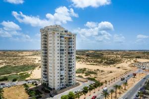 a tall white building in the middle of the desert at Ocean View Oasis with Balcony for families in Ashdod