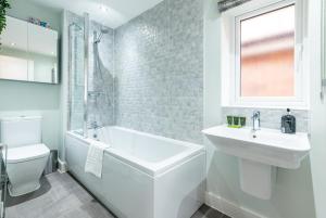 La salle de bains est pourvue d'un lavabo, d'une baignoire et de toilettes. dans l'établissement 4 Bedroom Detached House Ideal for Families and Corporate Stays in Radcliffe on Trent, à Burton Joyce