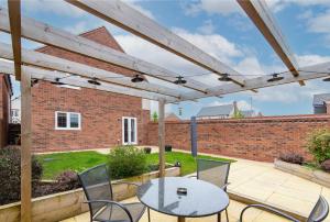 patio con mesa, sillas y pared de ladrillo en 4 Bedroom Detached House Ideal for Families and Corporate Stays in Radcliffe on Trent, en Burton Joyce