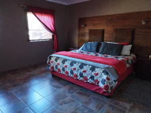 een slaapkamer met een groot bed en een rode deken bij Carstens Cove in Carletonville