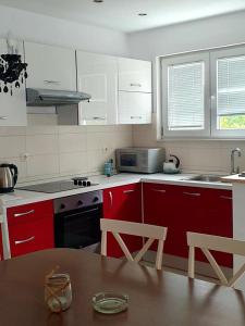 una cucina con armadi rossi e un tavolo in legno con tavolo in legno di Apartments Perina a Tisno (Stretto)