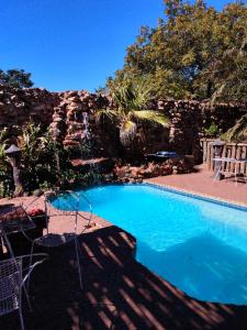 a large blue swimming pool next to a stone wall at Carstens Cove in Carletonville