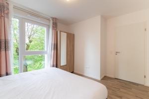 ein Schlafzimmer mit einem weißen Bett und einem großen Fenster in der Unterkunft Moulin à Vent Sud - Appt à 20 min de Paris in Bondy