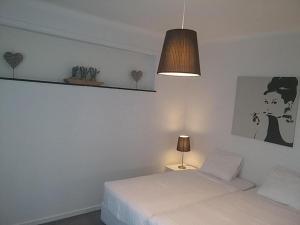 a white bedroom with a bed and a lamp at VILLA EXPO in Brussels