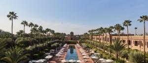 un complexe avec une piscine, des palmiers et un bâtiment dans l'établissement Selman Marrakech, à Marrakech
