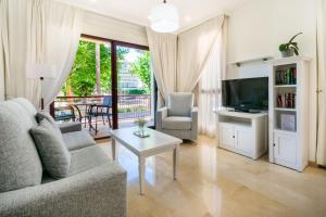 ein Wohnzimmer mit einem Sofa, einem TV und einem Tisch in der Unterkunft Apartamentos Albir Confort - Avenida 1 dorm in Albir