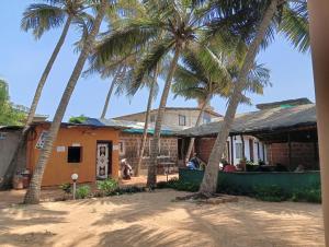 a group of palm trees in front of a house at Redkar Rooms Gokarna Beach front AC And Non AC Rooms in Gokarn