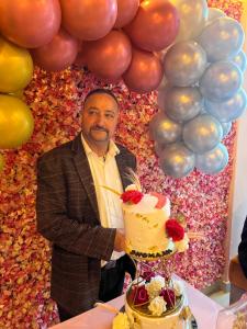 a man standing next to a table with a cake at Shomaan boutique hotel in Sundarnagar
