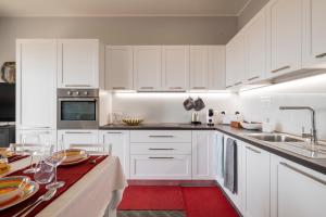 a white kitchen with white cabinets and a red rug at Vista Sulle Colline in Forlì