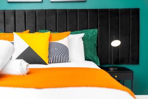 a bed with an orange blanket and colorful pillows at Luxury 3 Bedroom Apartment - Terrace - WiFi - Smart TV 1MR in Birmingham