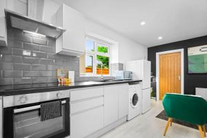 una cocina con electrodomésticos blancos y una silla verde en Luxury 3 Bedroom Apartment - Terrace - WiFi - Smart TV 1MR en Birmingham