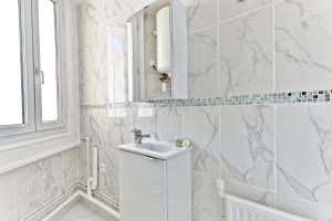 Baño blanco con lavabo y espejo en Appartement proche de Paris - Gagny, en Gagny