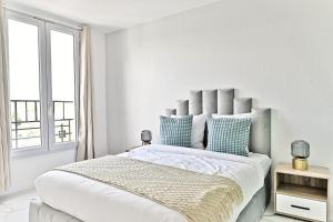 1 dormitorio blanco con 1 cama grande con almohadas azules en Appartement proche de Paris - Gagny, en Gagny