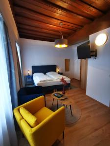 ein Wohnzimmer mit einem gelben Sofa und einem Bett in der Unterkunft Gasthof zur Sonne in Übelbach