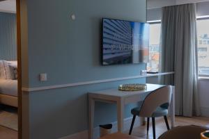um quarto com uma mesa e uma televisão na parede em VIP Executive Suites do Marquês Hotel em Lisboa