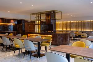 a restaurant with wooden tables and yellow chairs at VIP Executive Suites do Marquês Hotel in Lisbon