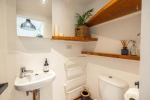 a small bathroom with a toilet and a sink at Jungle Cottage Escape in Auckland
