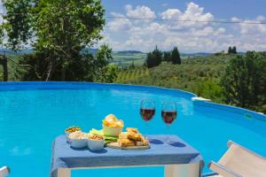 una mesa con dos copas de vino y comida junto a una piscina en Fattoria la Luna 15 min da Firenze Bilocale la Stalla piscina e wi fi en Lastra a Signa