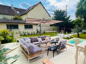 patio con divano e ombrellone di Pool Villa 25 min from Paris a Yerres