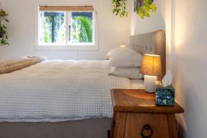 a bedroom with a white bed and a window at Jungle Cottage Escape in Auckland