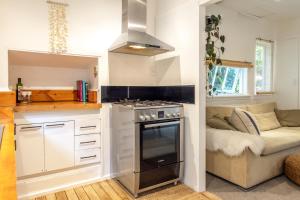 a kitchen with a stove top oven next to a couch at Jungle Cottage Escape in Auckland